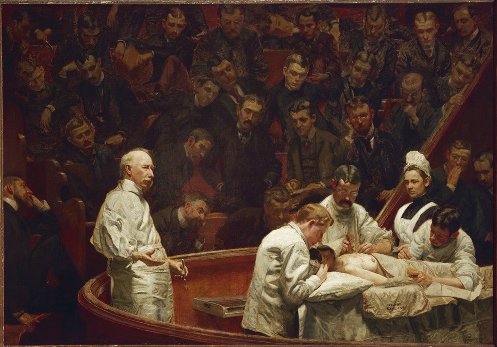 A surgical team operates on a patient in a bright operating theater, with surgeon David Agnew standing at left and nurses and assistants gathered around the table as rows of spectators look on.