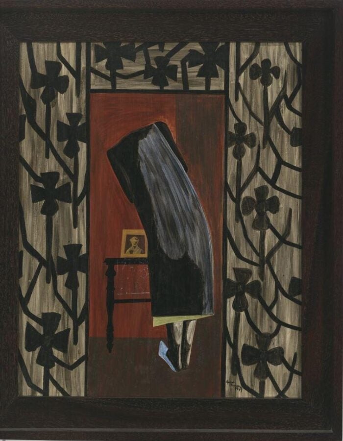 Painting of a veiled figure bending over a small table to look at a framed photograph, framed by patterned black floral designs on the walls.