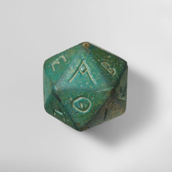 An ancient blue-green faience icosahedron die with Greek letters carved into each of its twenty faces.