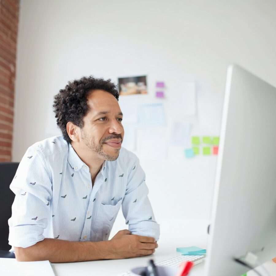 Person smiling at a desktop computer in a modern, bright office space.