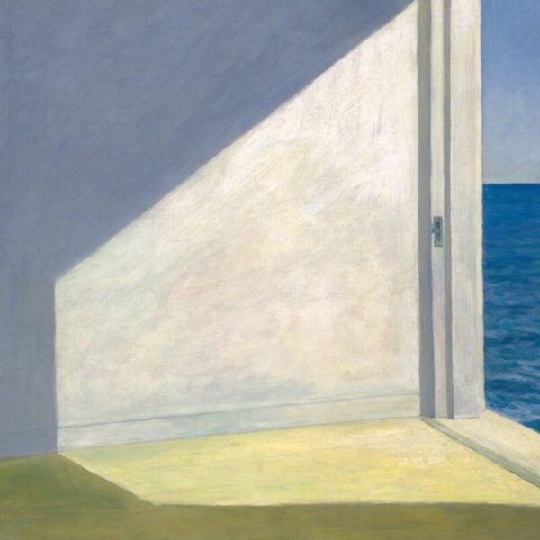 A sunlit room with an open doorway leading to a view of the blue ocean, casting strong geometric shadows across the interior floor and walls.