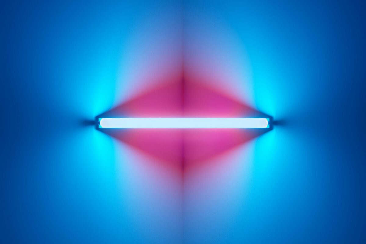 A horizontal neon light casting blue and pink glows symmetrically across a wall, creating a soft gradient of color.